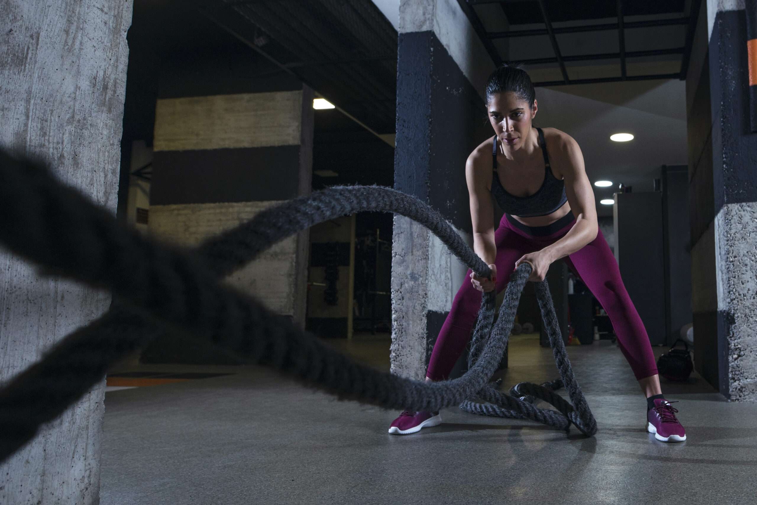 Fitness woman working out with battle ropes in the gym. and doing quick workouts